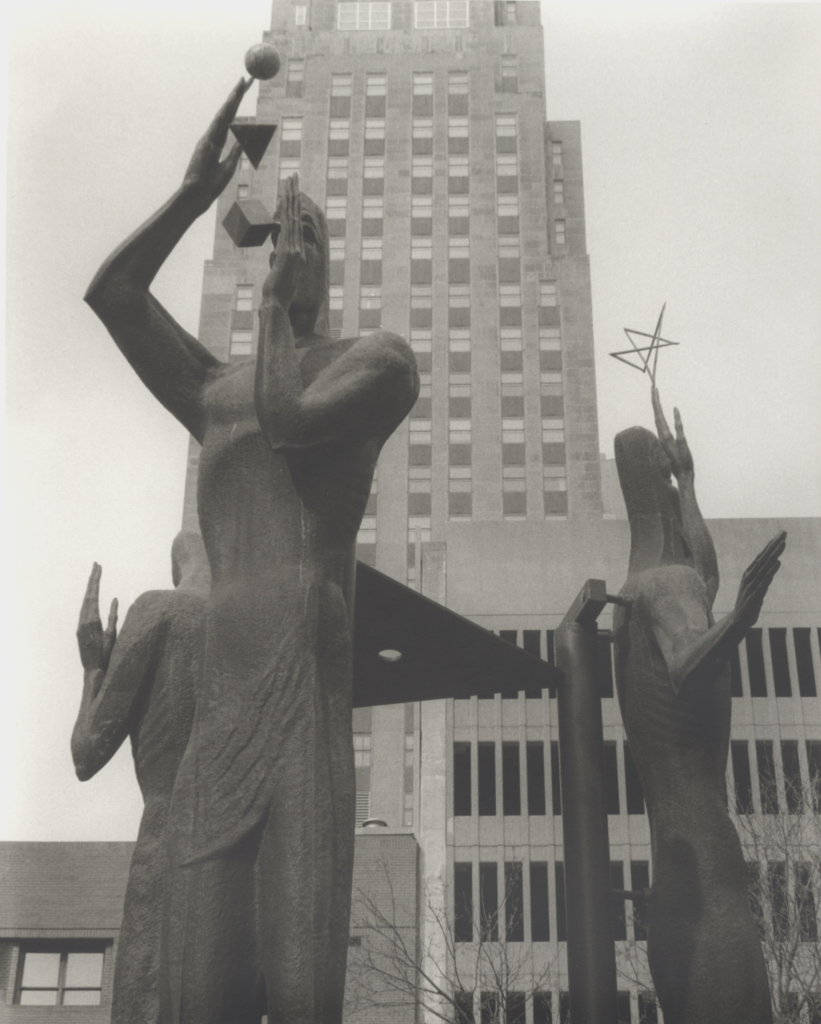 Statuary of three figures, one holding a star aloft while another juggles a ball, a quadrangle and a box.